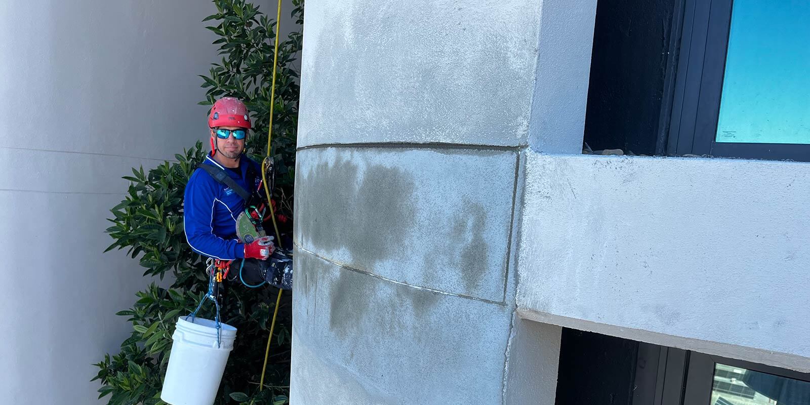 rope access worker repairing the concrete in a high rise building