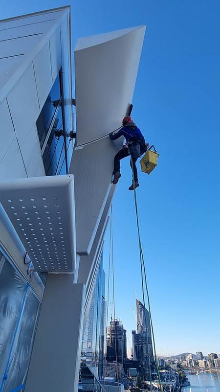 rope-access-worker-painting-modern-waterside-building