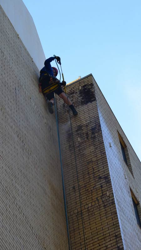 tall-brick-building-clean-by-abseiling-rope-access-worker